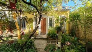 a yellow house with a tree in the front yard at La maison jaune près du métro in Montreuil