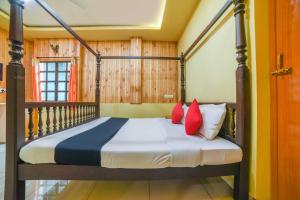a bedroom with a large bed with red pillows at Hotel O Auroville Beach Formerly Prince Park Garden in Kuilapayam