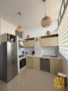 a kitchen with stainless steel appliances and two pendant lights at Golden Sunset - Appart'Hôtel in Antananarivo