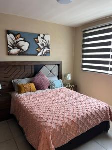 a bedroom with a bed with a pink comforter at Centrally located apartment with AC, parking and pool in Guadalajara +29 photos