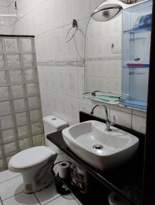 a white bathroom with a toilet and a sink at Casa com 1 cama de casal e 1 cama de solteiro in Serra +7 photos