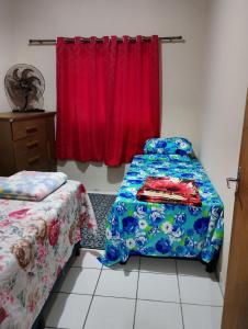 a room with two beds and a red curtain at Casa com 1 cama de casal e 1 cama de solteiro in Serra