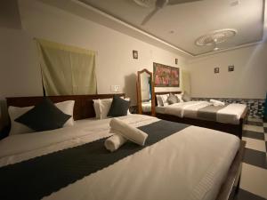 a bedroom with two beds with white sheets at Hotel Heaven In Jaisalmer in Jaisalmer