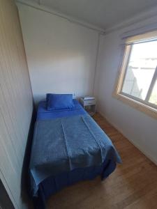 a bedroom with a bed with a blue comforter and a window at Central House in Punta Arenas +13 photos