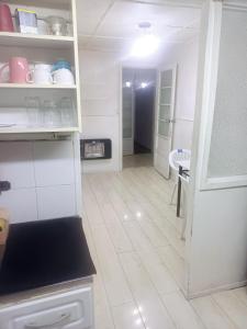 a kitchen with white cabinets and a white floor at Central House in Punta Arenas
