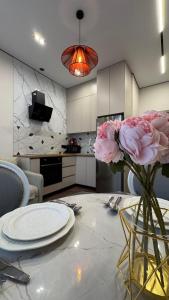 eine Küche mit einem Tisch mit einer Vase mit rosa Blumen in der Unterkunft DeLuXe CLASS HOME in Almaty
