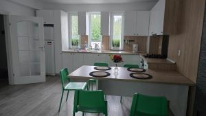 a kitchen with a table and green chairs at Casa Magurele 3 in Măgurele