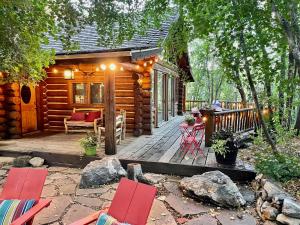 a cabin with a deck with red chairs and a table at Rustic Sundance cabin sleeps 13 hottub firepits in Sundance