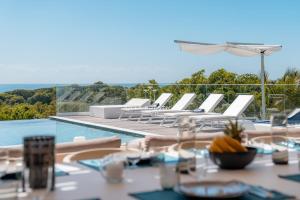 a table with white chairs next to a swimming pool at La Baie Du Pélican 3 rooms in Mare Gaillard +36 photos
