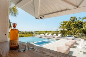 a bottle of wine sitting on a table next to a swimming pool at La Baie Du Pélican 3 rooms in Mare Gaillard