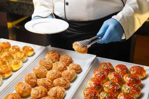 a person holding a spatula in front of trays of donuts at Queen T Juliana Beach Resort in Hurghada