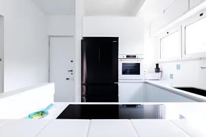 a kitchen with a black refrigerator and white cabinets at VILLA LILLA Beachfront - Sea View with Parking and Private Garden in Anzio