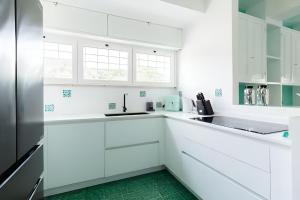 a white kitchen with white cabinets and a green floor at VILLA LILLA Beachfront - Sea View with Parking and Private Garden in Anzio