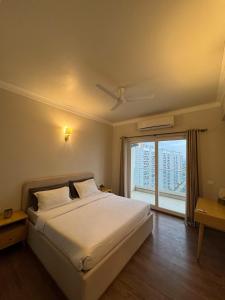 Un dormitorio con una cama y una ventana grande. en Central Park, The Rooms 1 & 2 BHK Spacious Pool view apartment, en Gurgaon