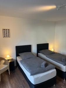 two beds in a room with a table and a chair at Gästehaus Gerschler in Garbsen