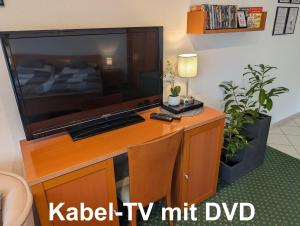 a large flat screen tv sitting on top of a desk at Apartment mit Balkon und Pool, zentral am Waldrand in Bad Essen +9 photos