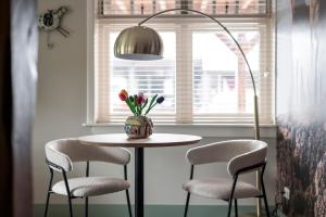 a table with two chairs and a vase with flowers at Bed and Breakfast de Hoge Enk in Ons Belang +7 photos