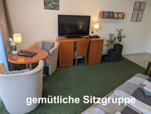 a living room with a television and a table and chairs at Apartment mit Balkon und Pool, zentral am Waldrand in Bad Essen