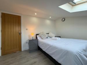 1 dormitorio con 1 cama blanca grande y puerta de madera en Britlodge Living, en Mánchester