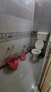 Un baño con inodoro y cubos dentro. en DYO Agrasan Bhavan, en Dwarka