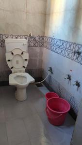 baño con aseo y 2 cubos rojos en DYO Agrasan Bhavan, en Dwarka