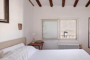 a white bedroom with a bed and a window at The Terrace of San Pellegrino - Historic Center in Viterbo