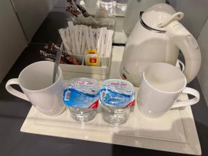 Un estante en un refrigerador con dos tazas y una tetera. en Petra night hostel, en Wadi Musa