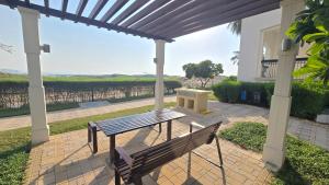 un banc en bois sous une pergola avec une table dans l'établissement F1 - Ivy Studio Golf View Ansam Yas Island, Theme Parks, à Abu Dhabi