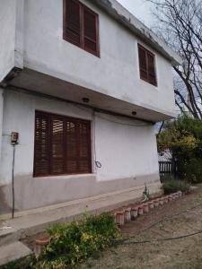 a white house with brown shuttered windows at Altos nieva in San Salvador de Jujuy