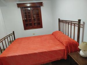 a bed with an orange blanket on top of it at Altos nieva in San Salvador de Jujuy
