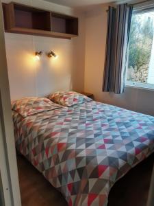 Un dormitorio con una cama con un edredón colorido. en Mobil home des gorges de provence, en Montagnac