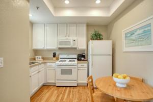 a kitchen with a table and a white refrigerator at Pacific Plaza #509 - Lighthouse Lodge - 1BdrmUp-K-QSofa in Oceano