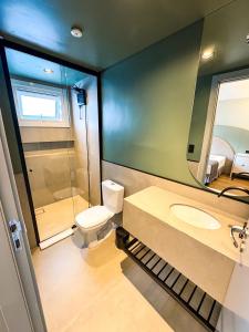 um banheiro com um vaso sanitário, uma pia e um espelho em Hotel Zata - Premium em Criciúma