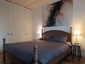 a bedroom with a bed and a painting on the wall at Pievų Tako kiemelis in Klaipėda
