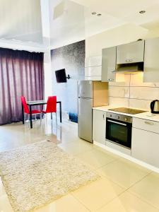 Квартири подобово центр في دنيبروبيتروفسك: مطبخ مع دواليب بيضاء وطاولة مع كراسي حمراء