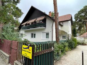 a house with a fence with a sign on it at Balaton-Lak Apartmanház in Siófok
