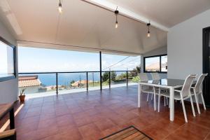 ein Esszimmer mit einem Tisch und Meerblick in der Unterkunft Casa do Paulinhos in Estreito da Calheta