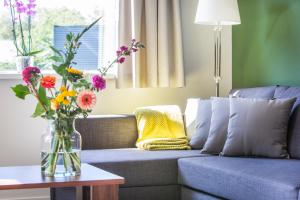 Una sala de estar con un sofá azul con flores en un jarrón. en Landgoed Leudal - In de natuur nabij Roermond, en Haelen