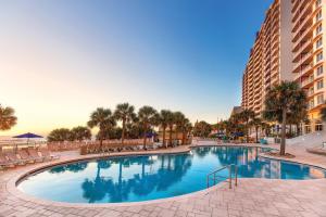 a large swimming pool with palm trees and a building at Ocean Walk Resort in Daytona Beach