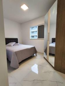 ein Schlafzimmer mit einem Bett und einem Spiegel in der Unterkunft Residêncial Campinas a 400 Metros da praia de Palmas in Governador Celso Ramos