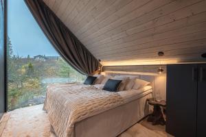 a bed in a room with a large window at Aura Arctic Chalets - Grand Panoramic & Grand Hideaway in Saariselka
