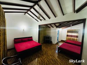 a room with two red beds and a couch at SkyLark Guest House in Nawalapitiya