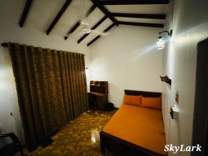 a bedroom with an orange bed and curtains at SkyLark Guest House in Nawalapitiya