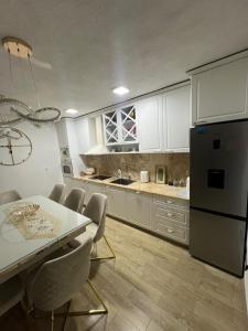 a kitchen with white cabinets and a table and a refrigerator at Luxury home in the city centre in Prilep