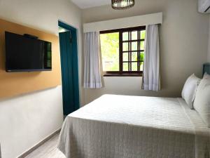 Un dormitorio con una cama y un televisor y una ventana. en Ilha Deck Hotel, en Ilhabela