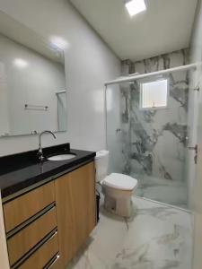 ein Badezimmer mit Toilette, Waschbecken und Dusche in der Unterkunft Residêncial Campinas a 400 Metros da praia de Palmas in Governador Celso Ramos