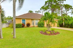a yellow house with palm trees in a yard at 15 Mi to Melbourne Beach Peaceful Palm Bay Escape in Palm Bay