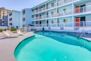 Una piscina frente a un hotel con sillas y un edificio. en 4 Mi to Barefoot Landing Retreat with Pool Access!, en Myrtle Beach