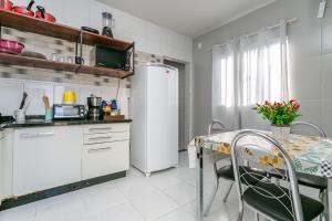a kitchen with a table and a white refrigerator at Casa perto do centro e da Udesc Cefid in Florianópolis