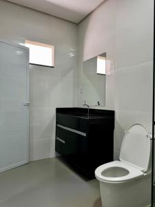 a white bathroom with a toilet and a sink at Villa Hotel in Bom Jesus da Lapa